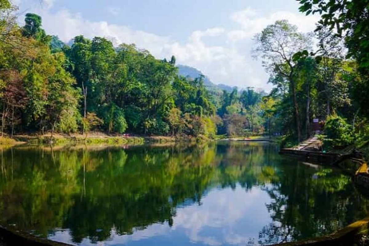 Serene view of Sally Lake near Roing with a tourist lodge and thick green forest background.