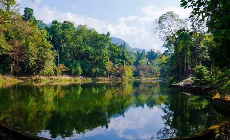 Serene view of Sally Lake near Roing with a tourist lodge and thick green forest background.
