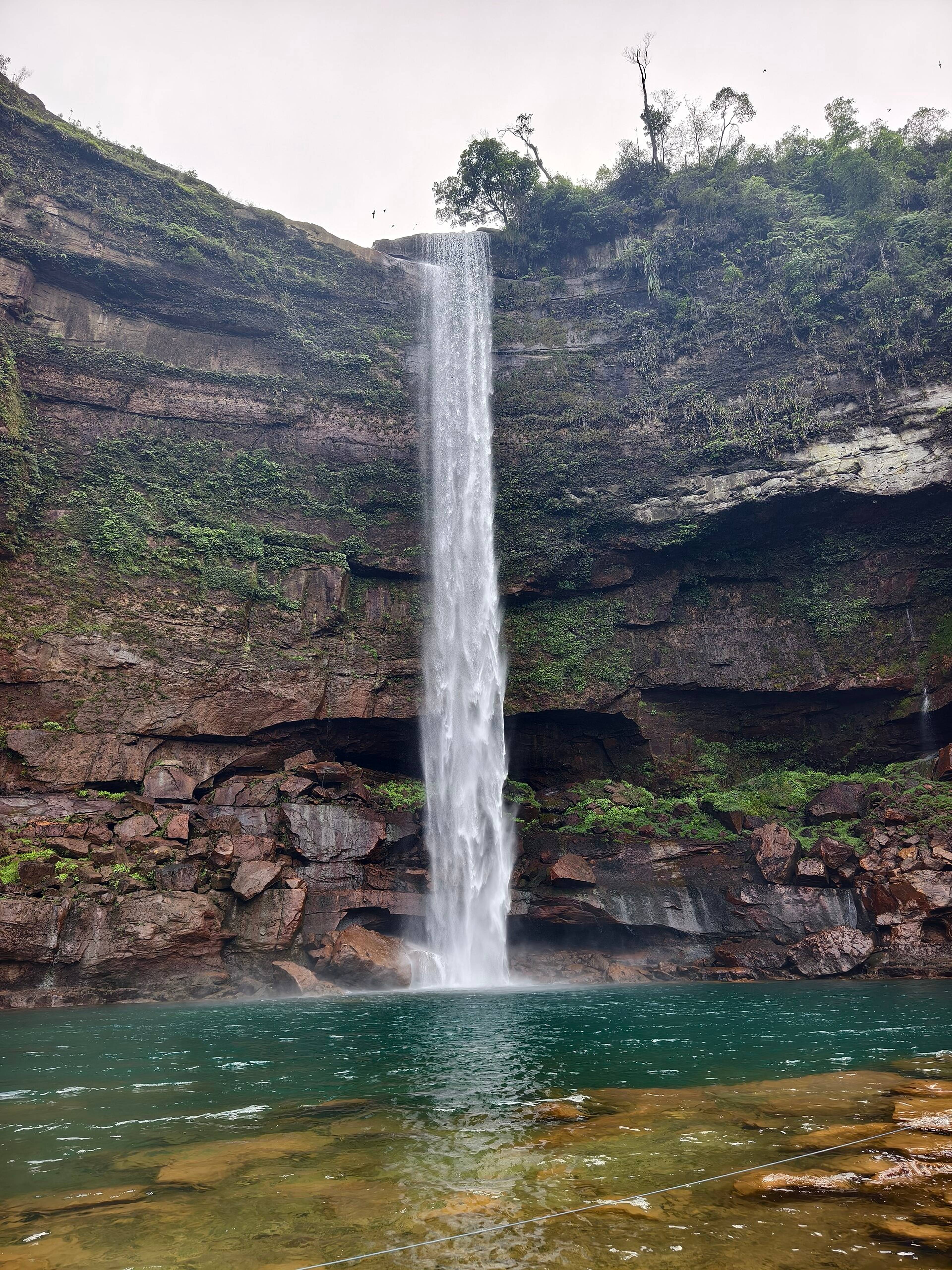 Phe Phe waterfall falling into a turquoise pool in a rocky gorge near Jowai