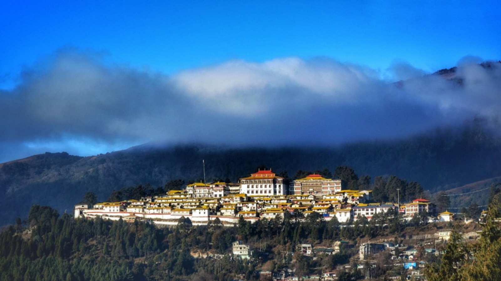 Tawang Monastery in Arunachal Pradesh, the second-largest Buddhist monastery in the world, shown against a backdrop of snow-capped Himalayan peaks.