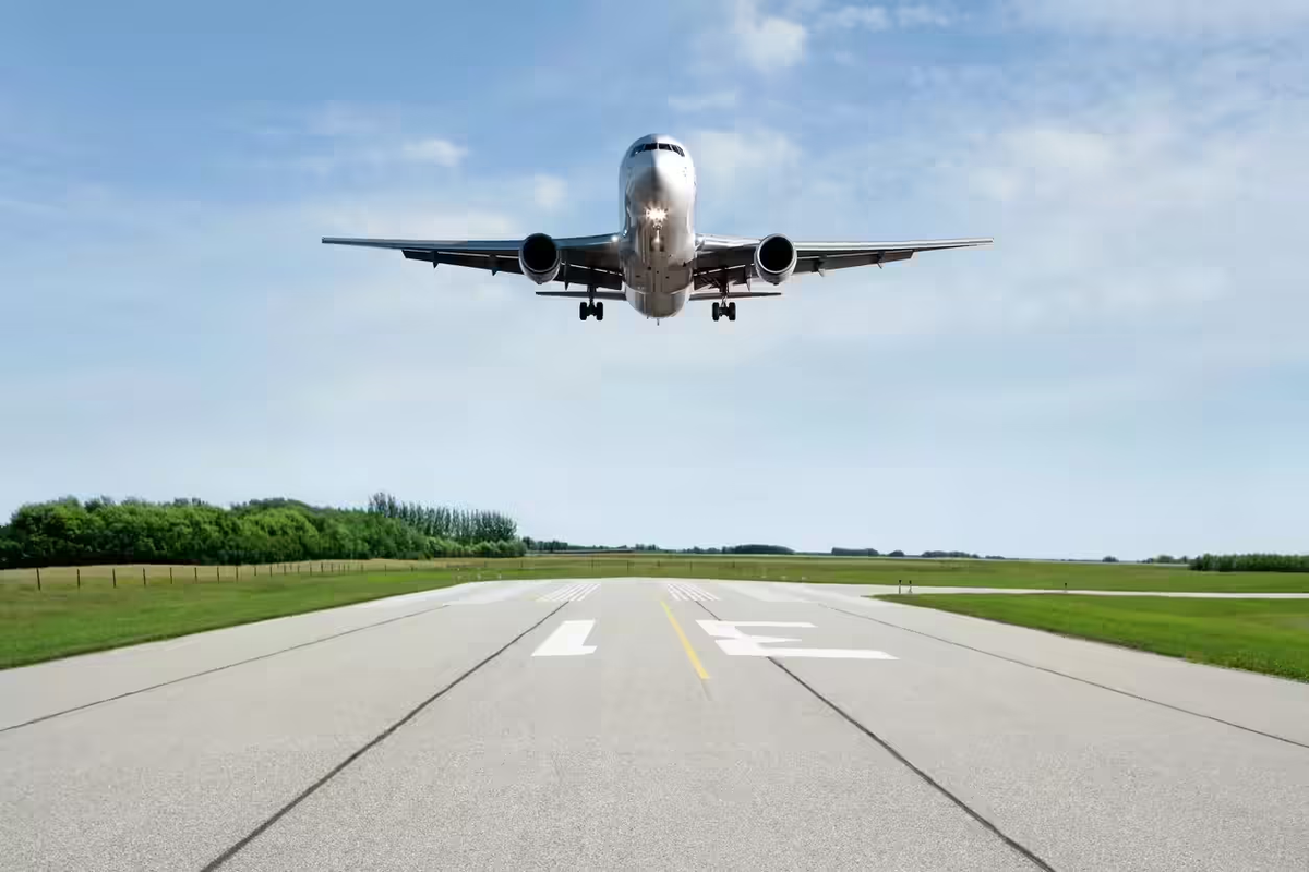 A passenger plane landing at Guwahati airport surrounded by green trees.