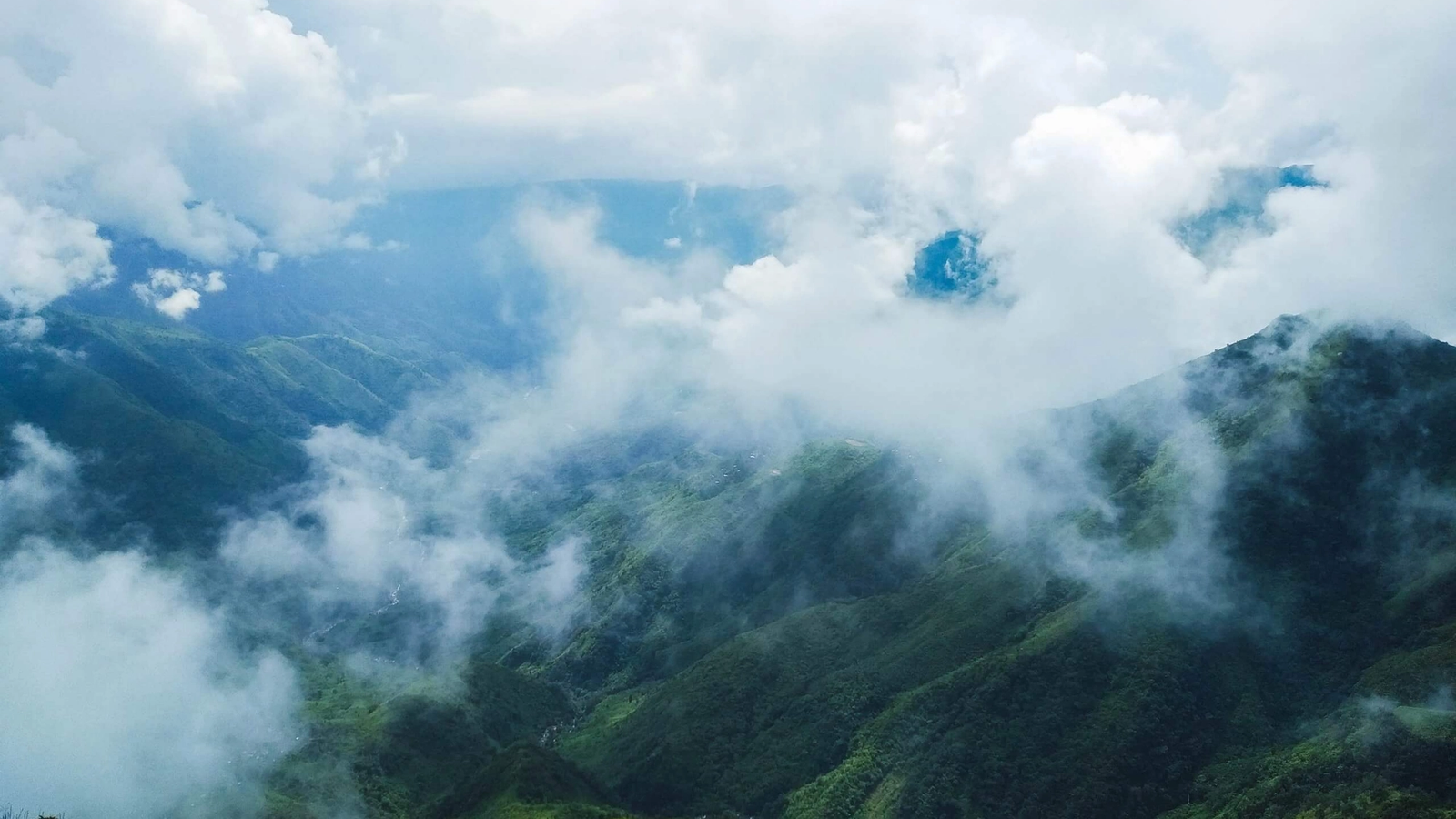 A breathtaking aerial view of the emerald, green hills and misty clouds of Meghalaya, India.