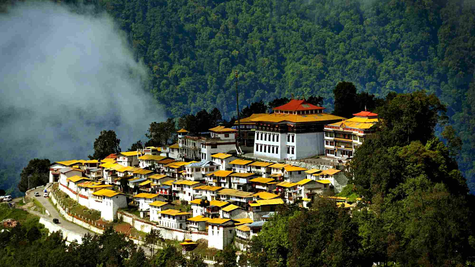 Alt Text Tawang Monastery perched on hilltop surrounded by Himalayan peaks and prayer flags in Arunachal Pradesh, Northeast India