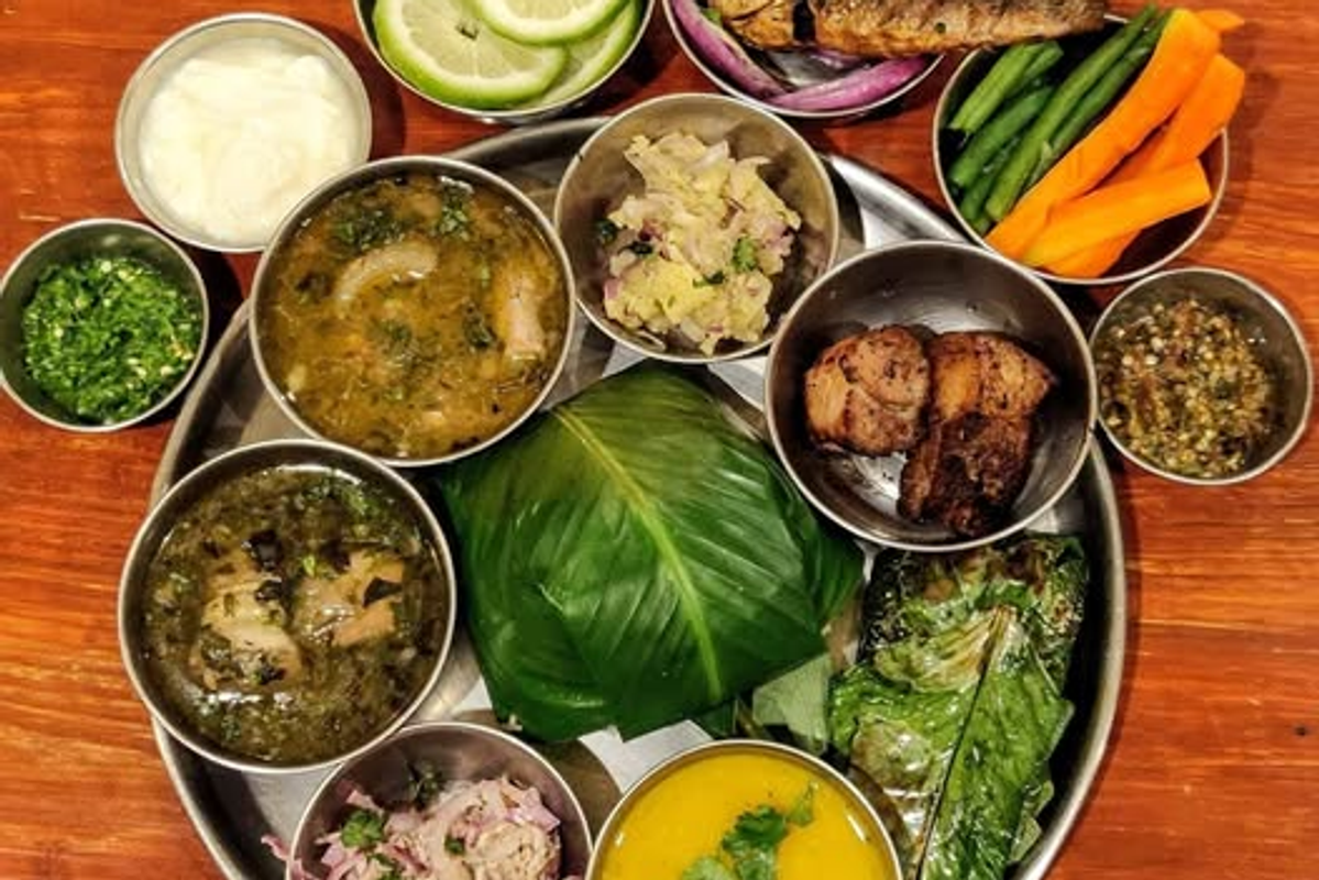Traditional Apatani food platter with bamboo-shoot pork and rice beer served in a bamboo tumbler.
