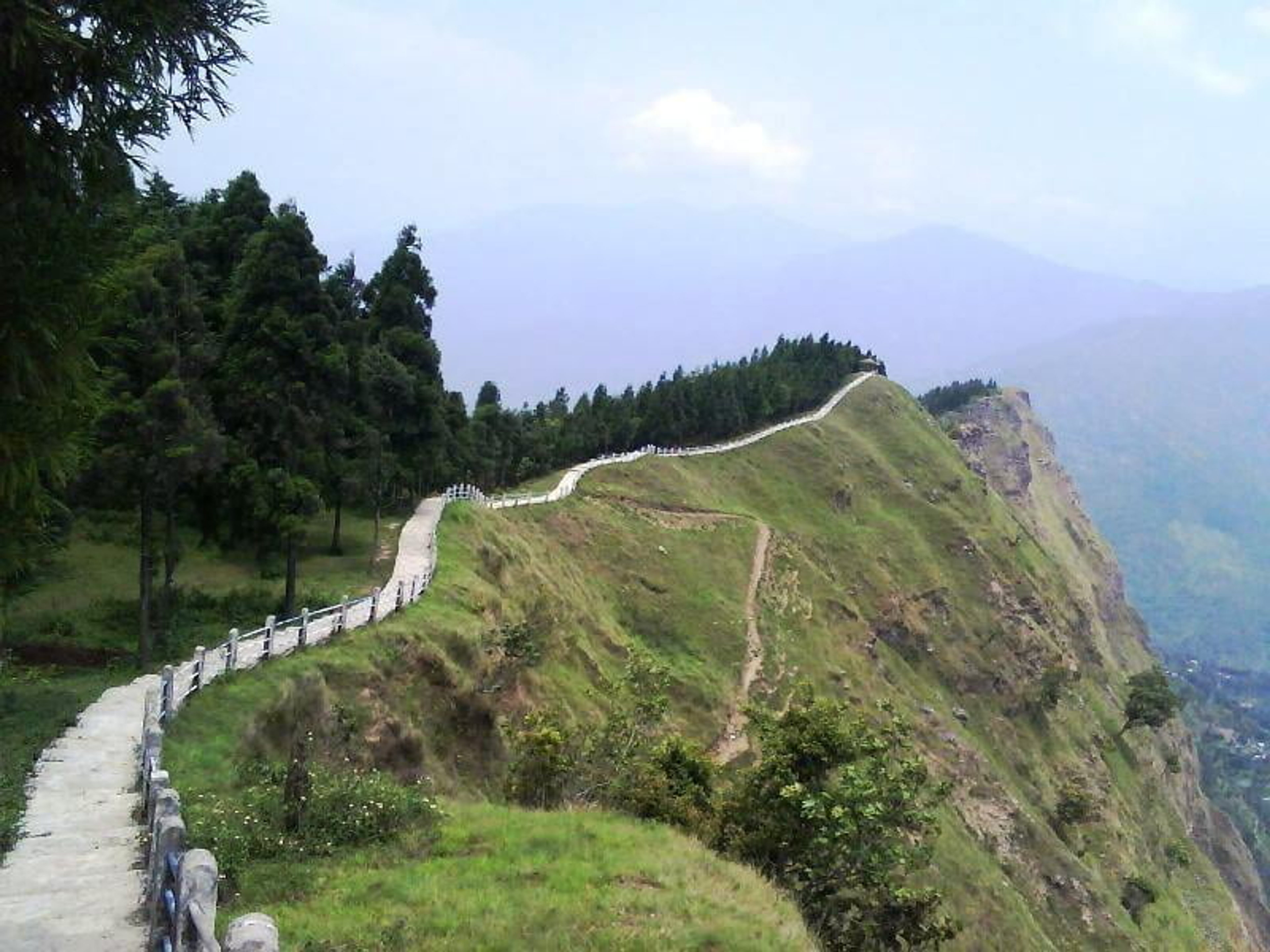 A long stone walkway on the Tarey Bhir ridge showing a dramatic cliff drop and the river confluence below.