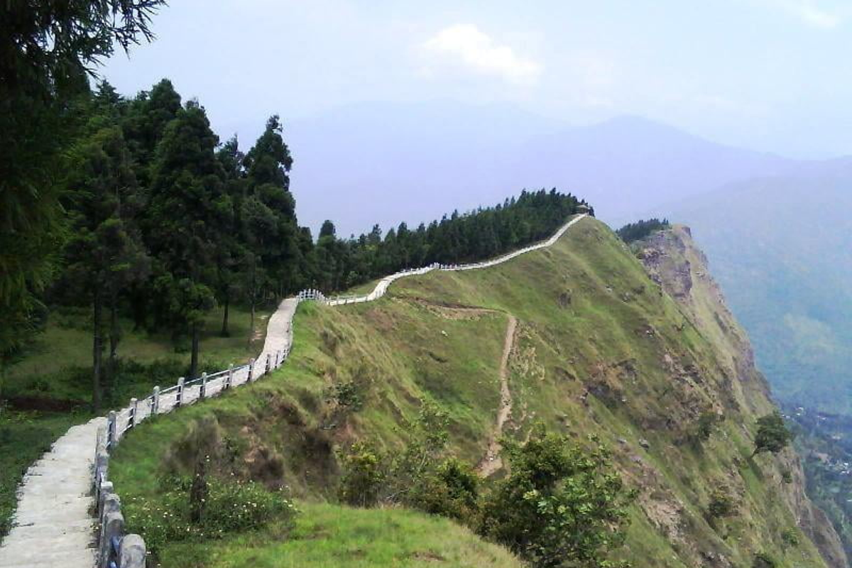 A long stone walkway on the Tarey Bhir ridge showing a dramatic cliff drop and the river confluence below.