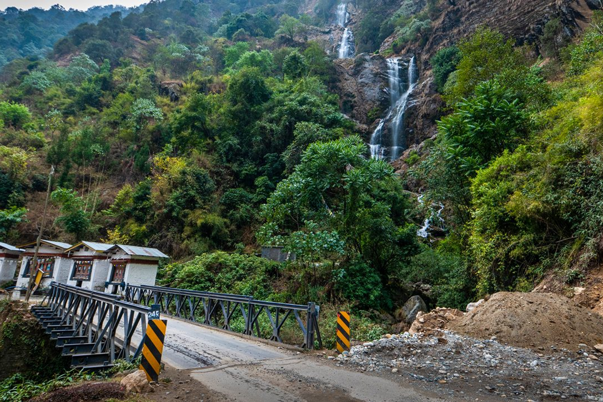 The multi-tiered Bap Teng Kang Waterfall (BTK Falls) in Tawang, Arunachal Pradesh, cascading into a crystal-clear pool surrounded by lush Himalayan forest.