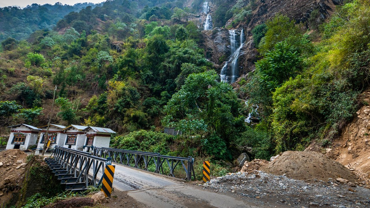 The multi-tiered Bap Teng Kang Waterfall (BTK Falls) in Tawang, Arunachal Pradesh, cascading into a crystal-clear pool surrounded by lush Himalayan forest.