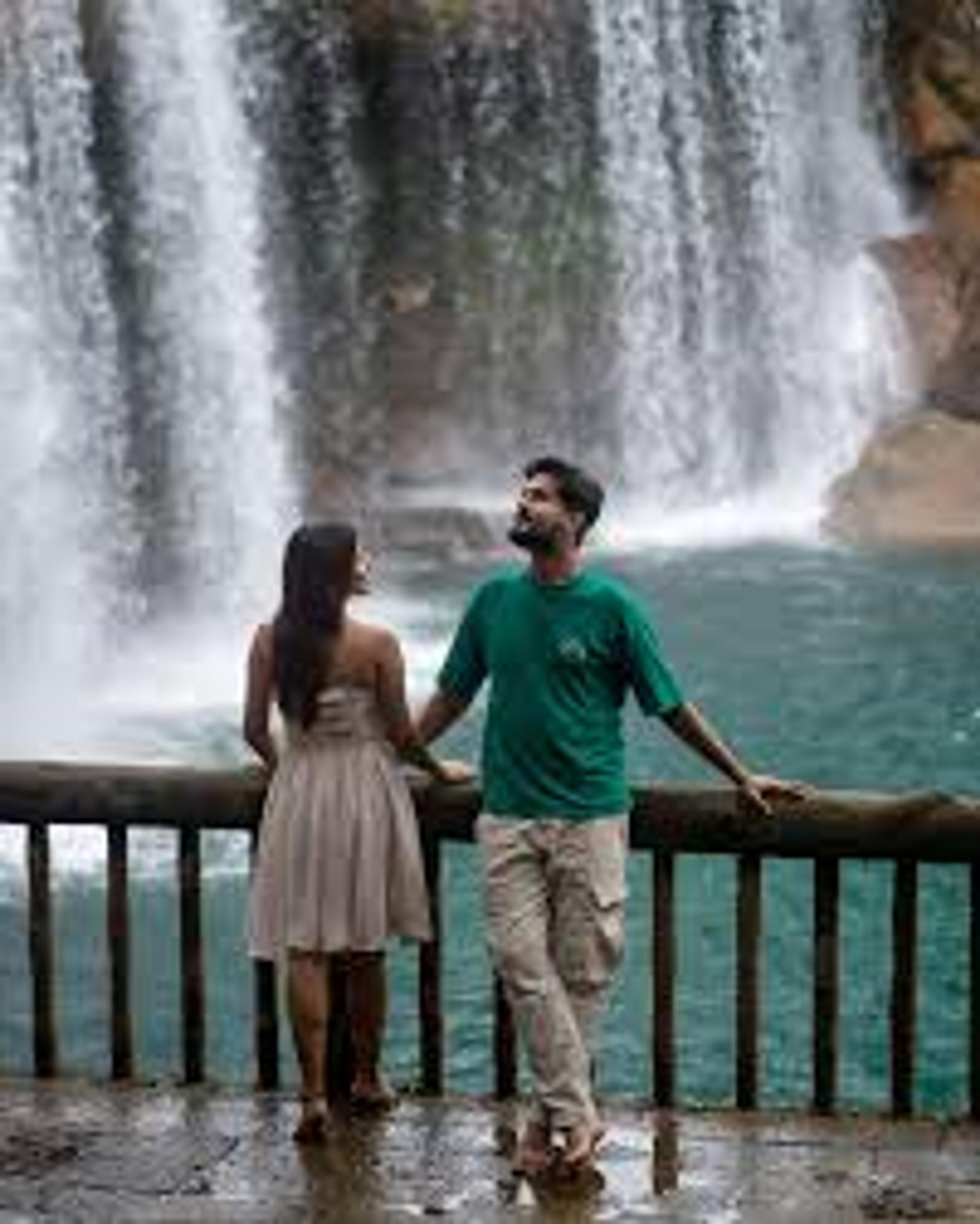 Romantic couple at Krang Suri Falls, Meghalaya, highlighting the turquoise water and lush greenery.]