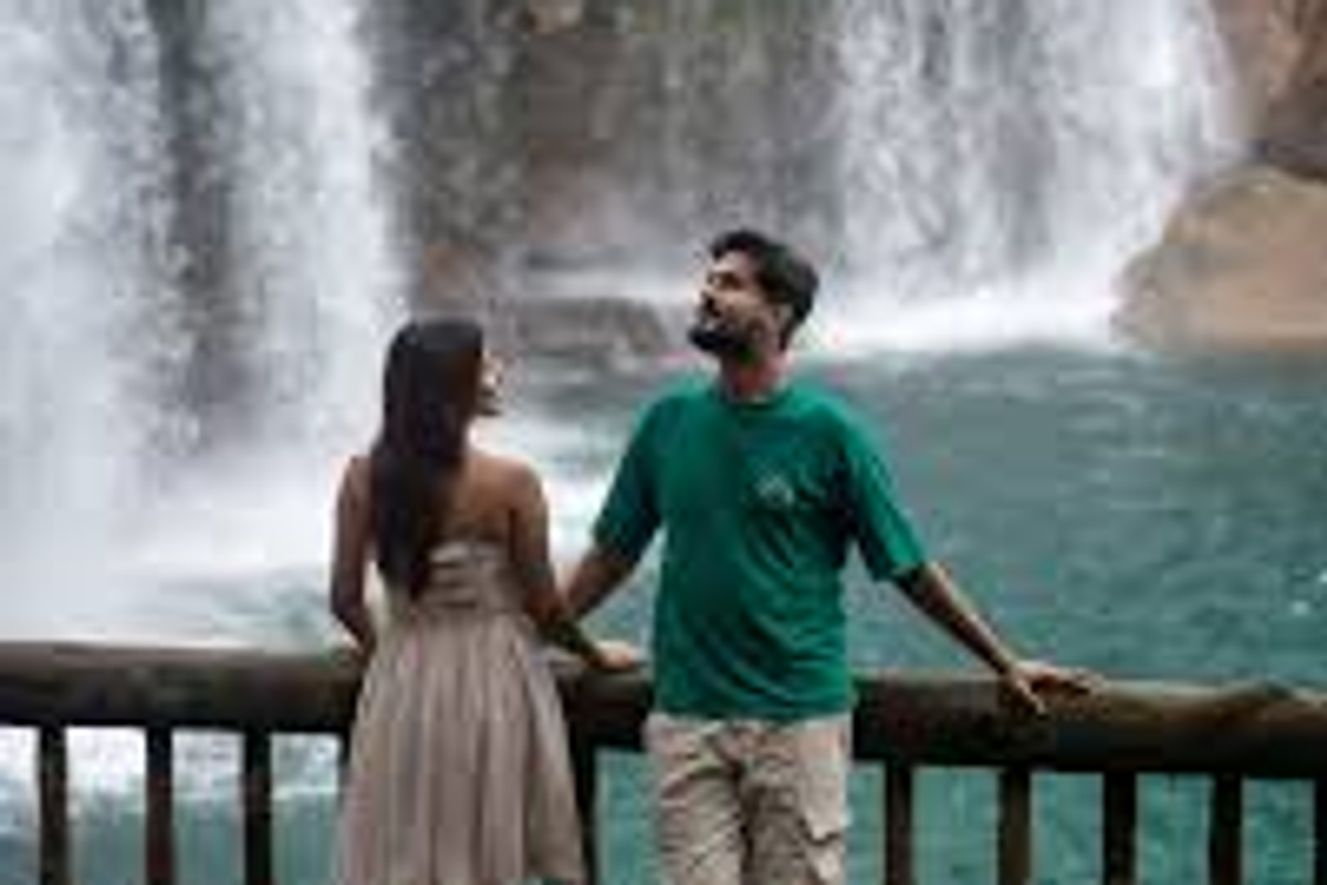 Romantic couple at Krang Suri Falls, Meghalaya, highlighting the turquoise water and lush greenery.]