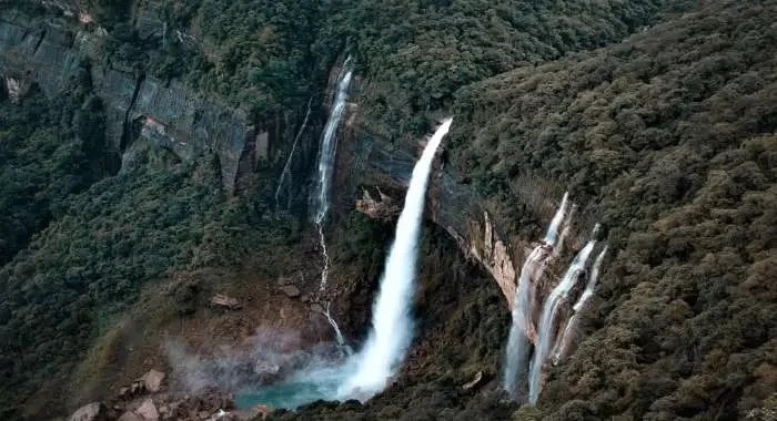 Tallest plunge waterfall in India Nohkalikai Falls crashing down a high limestone cliff into a green water pool below in Cherrapunji Meghalaya