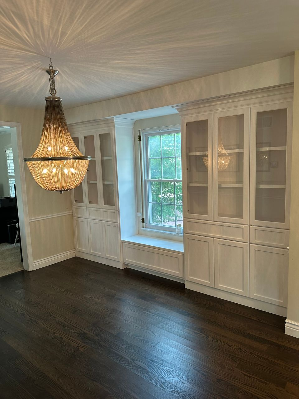 Floor-to-ceiling white glass-front cabinetry framing a custom window seat