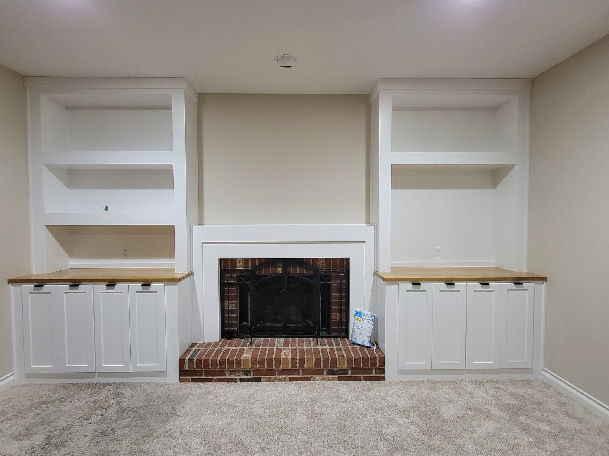 White built-in cabinets and shelving flanking a brick fireplace