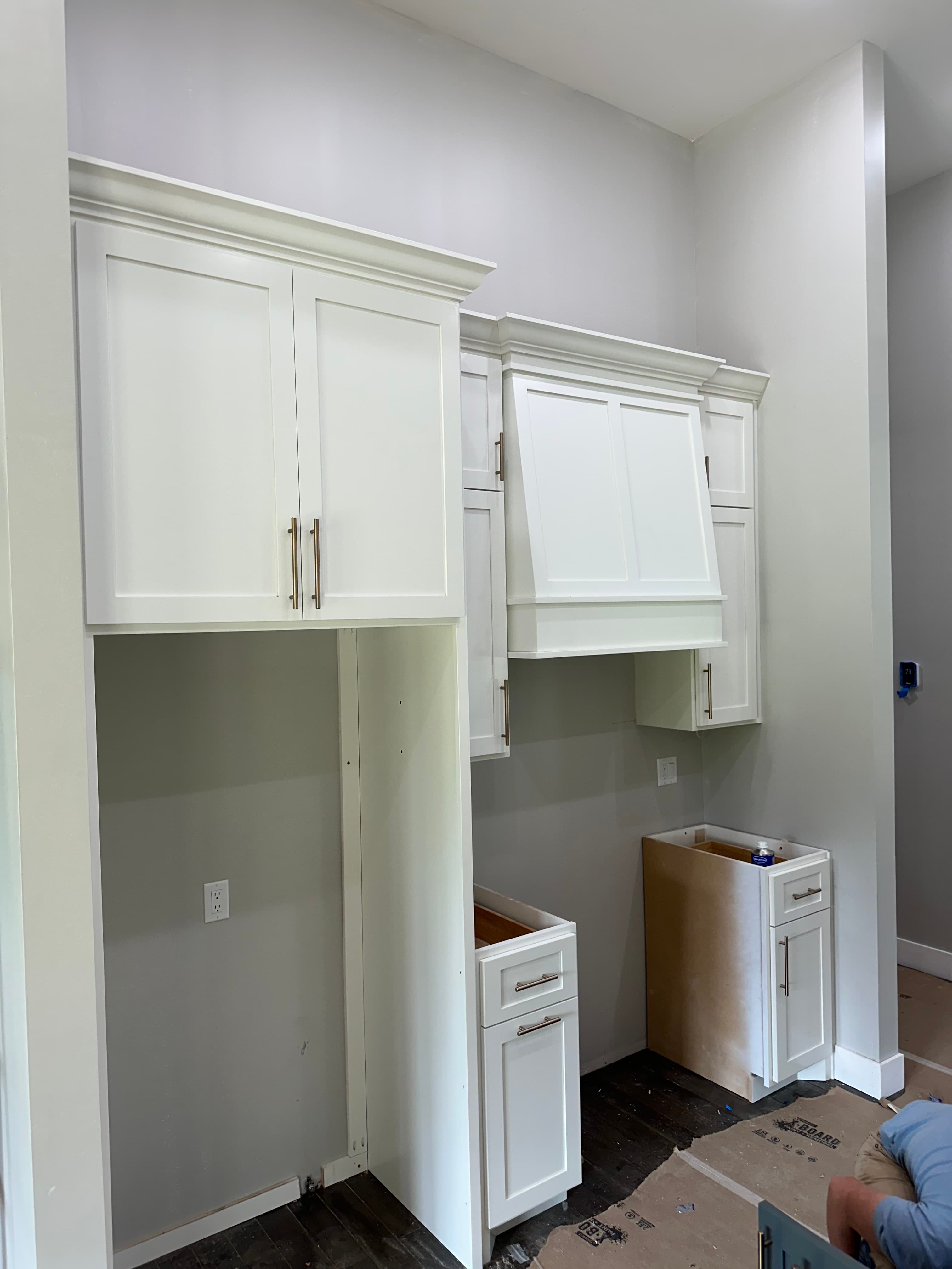 White custom utility room cabinets with appliance openings and brushed metal handles during installation