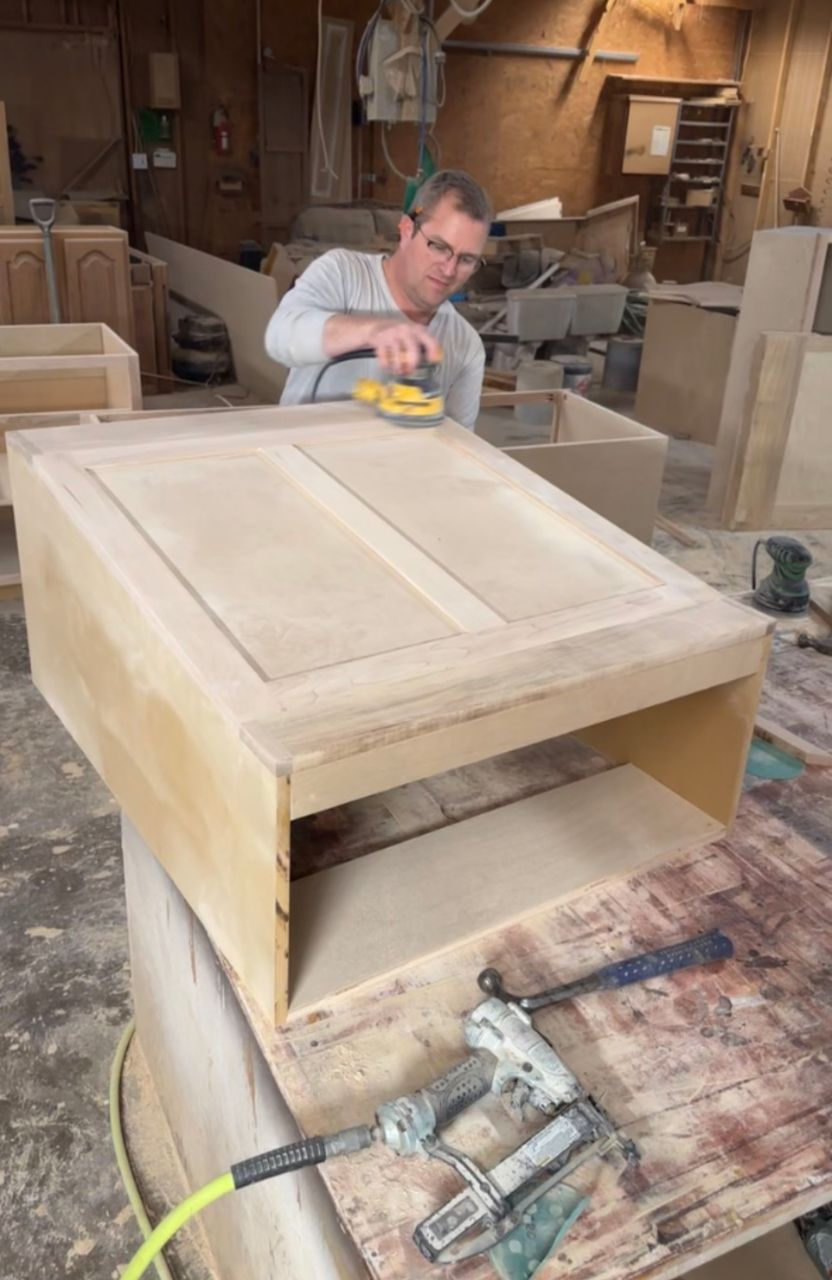 Nathan Green sanding a handcrafted raised-panel maple cabinet in his Mount Vernon workshop