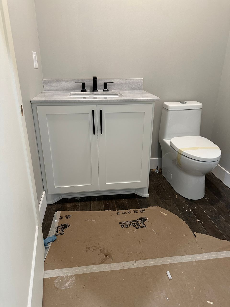 Compact white custom vanity with stone top and black fixtures fitted in a powder room