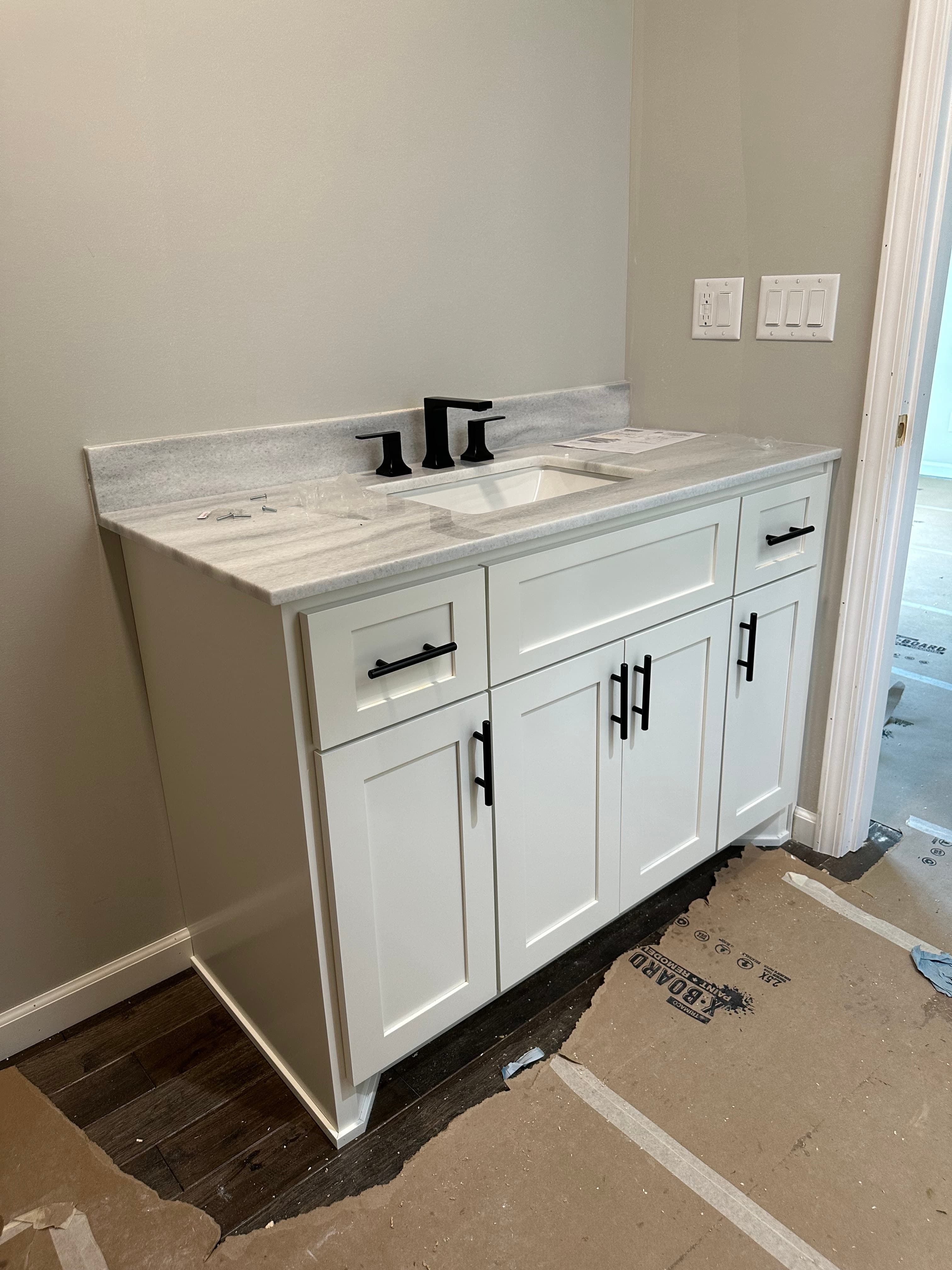 Custom white kitchen with dark island during installation