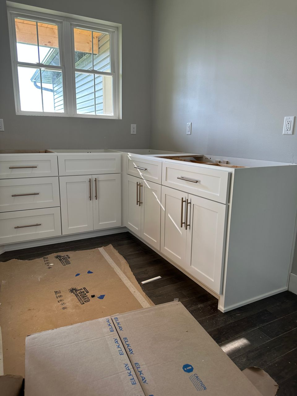 White Shaker base cabinets fitted around a corner beneath a double window
