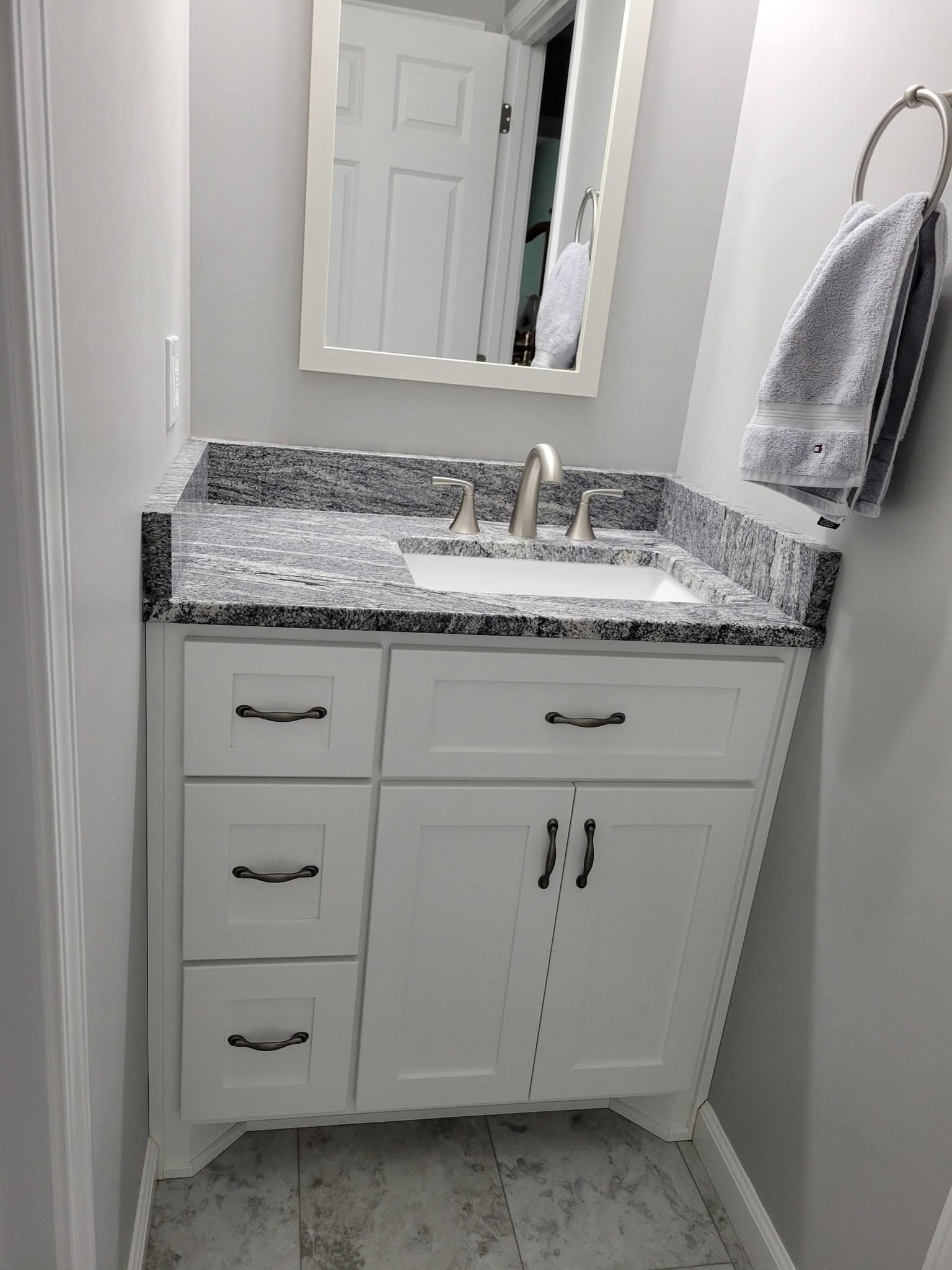 White bathroom vanity with granite top and framed mirror