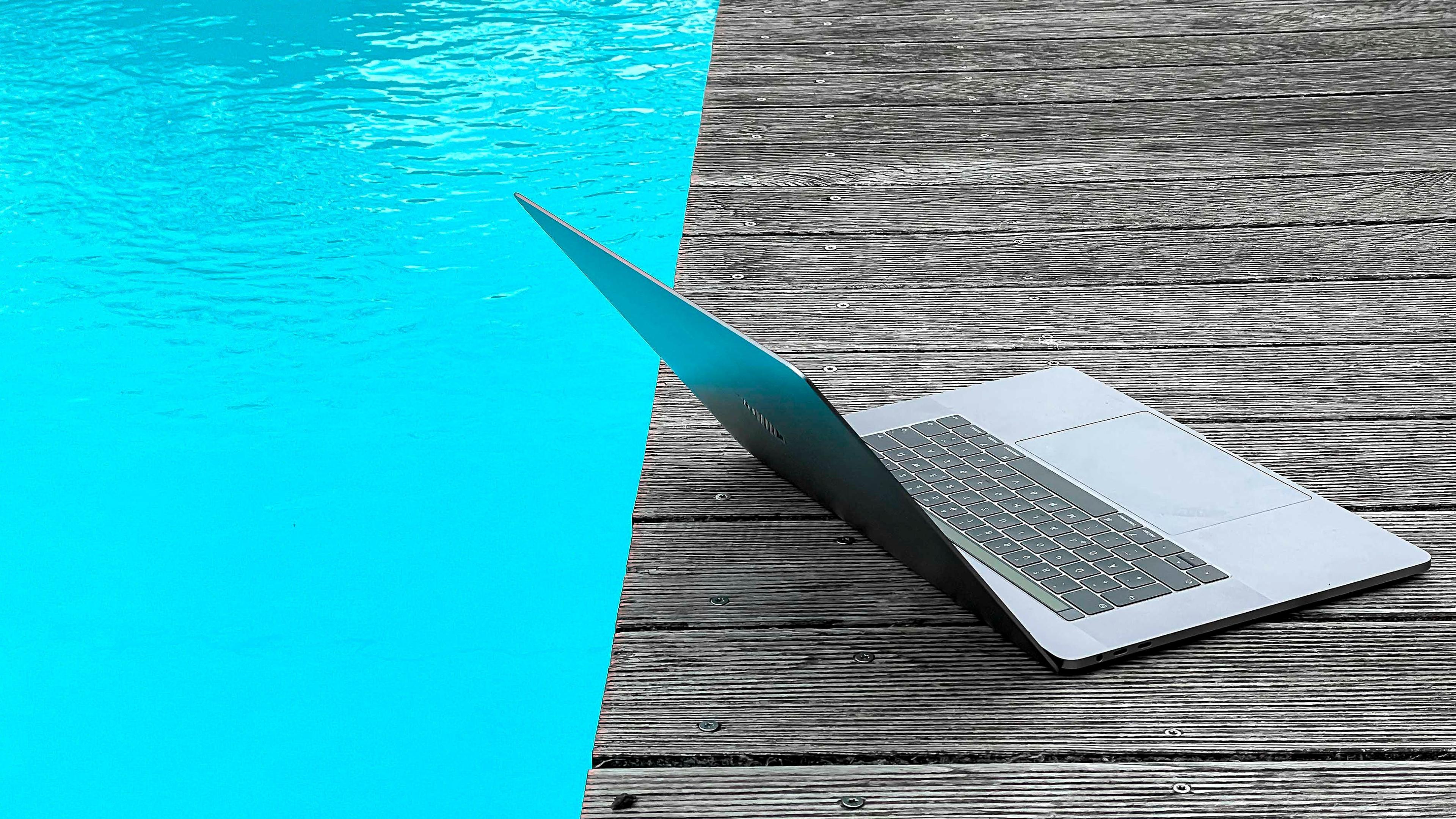 Ein Laptop steht am Beckenrand, neben einem Pool
