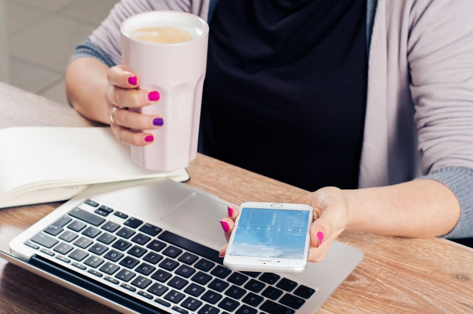 Woman using a cell phone and laptop at her desk