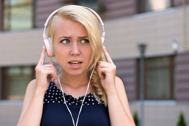 A young female wearing headphones that don't appear to be working