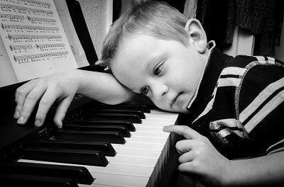 Young boy sleeping over a piano