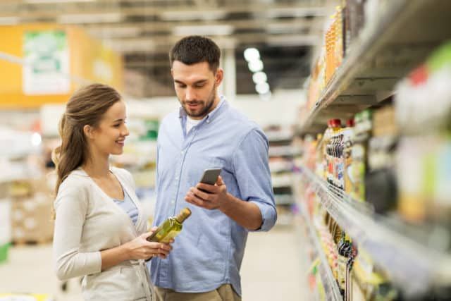 A couple discussing what groceries they need with the aid of a smartphone app