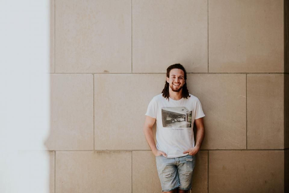 Smiling man standing along against a building