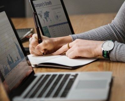 Woman writing while analyzing data