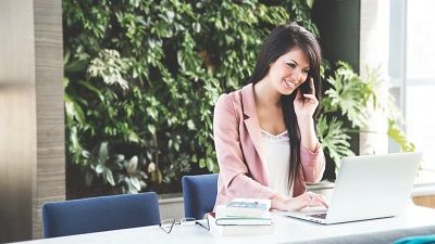 Woman on a mobile phone and using a computer at the same time