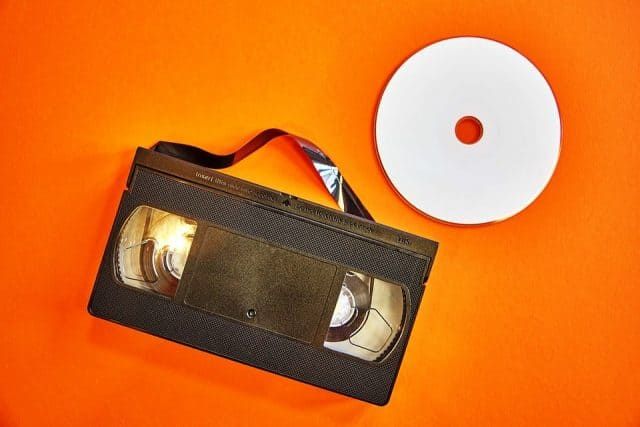 Concept of stream ripping with videocassette with tape pulled out next to DVD