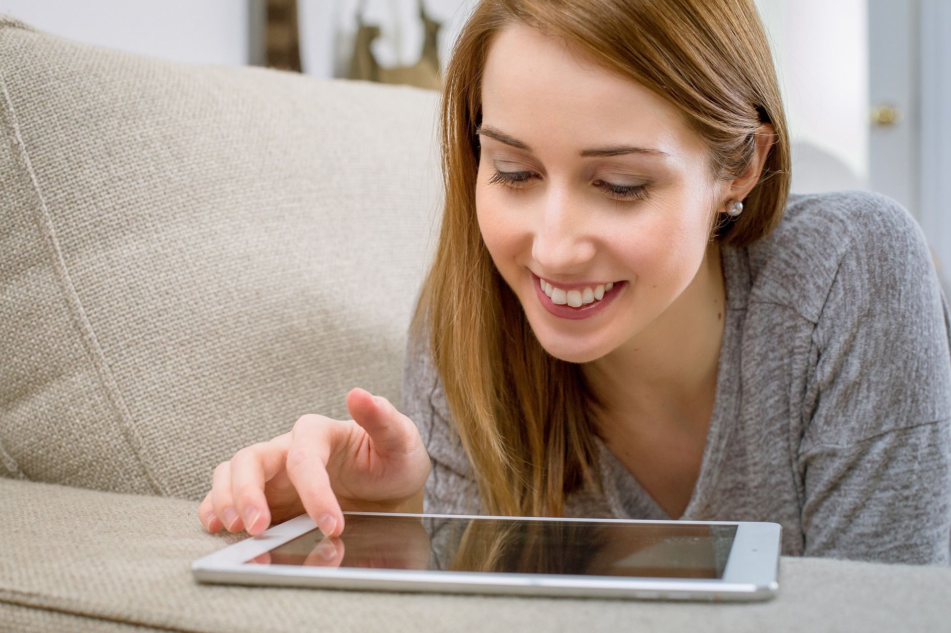 Woman relaxing while using a tablet device on a couch