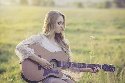 Woman playing a guitar in a field