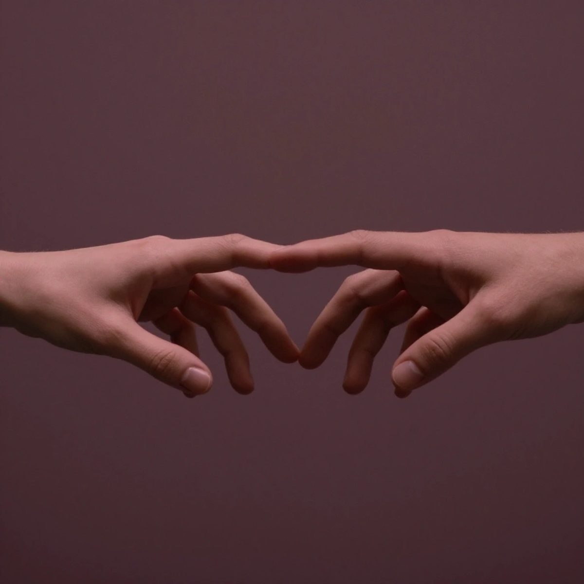 Two hands reaching toward each other with visible heart lines, bathed in warm volumetric light.