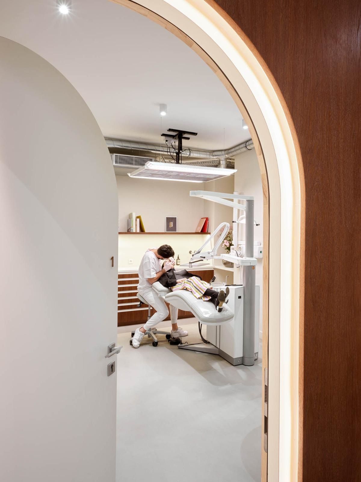 Salle de soins du cabinet, vue depuis le couloir à travers une porte en arche
