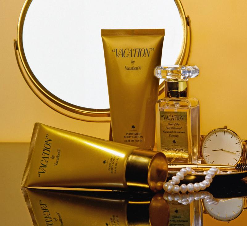 a bottle of perfume , lotion , and a watch are on a table next to a mirror .