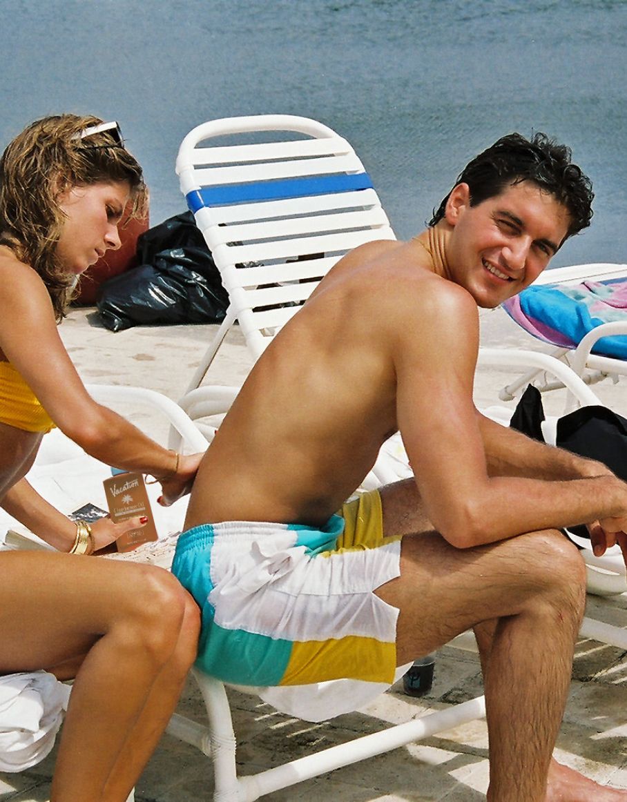 a man sits in a chair while a woman holds a vacation card