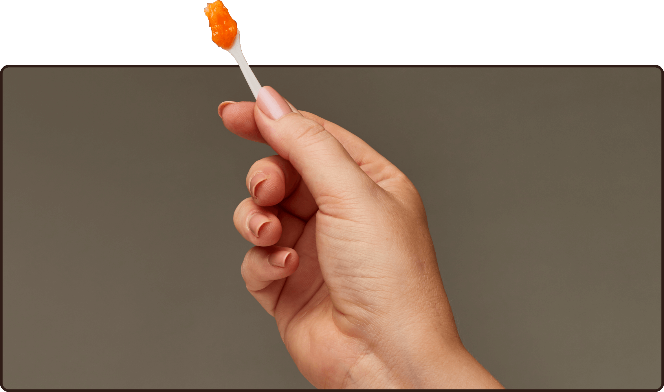 a hand holding a toothbrush with orange toothpaste on it
