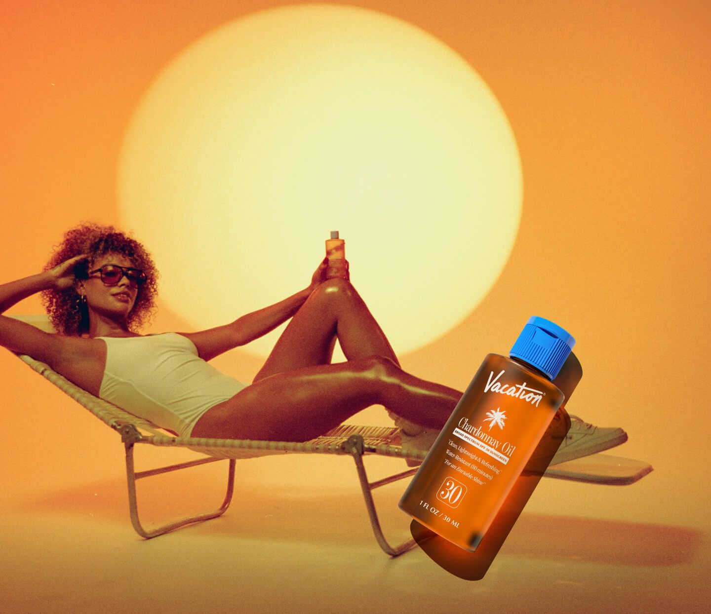 A woman in a white swimsuit lounges on a chair in the sunset