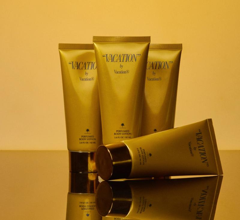 four tubes of "VACATION" by Vacation® Perfumed Body Lotion on a gold background