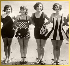 Four women in 1920s swimsuits smile and hold hands on a beach.
