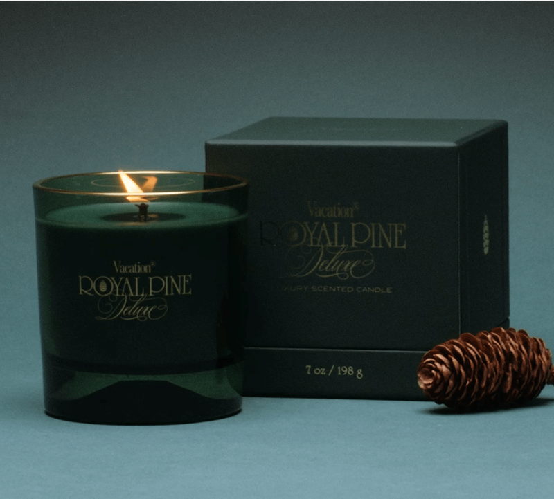 a vacation royal pine deluxe scented candle and box on a green background