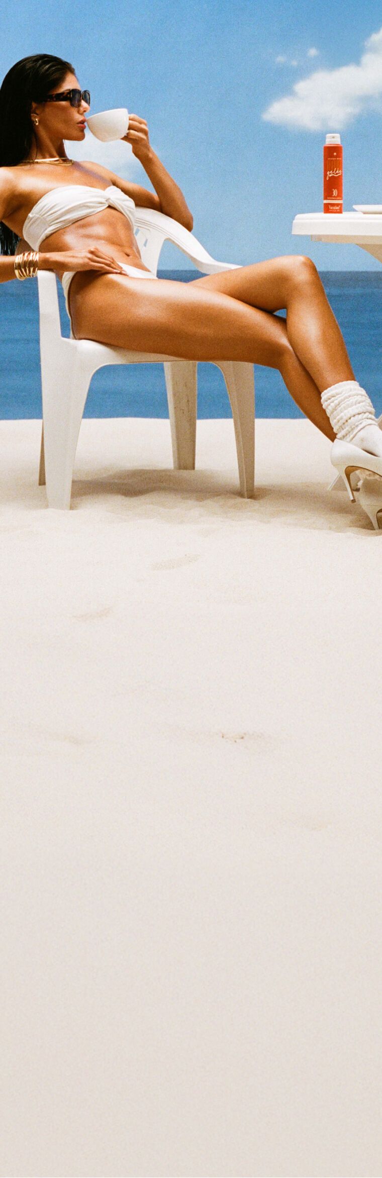 a woman sipping a cappuccino at a café table on the beach