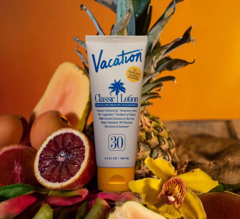 Vacation Classic Lotion SPF 30 sunscreen tube surrounded by tropical fruits and a yellow orchid.