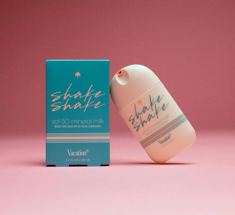 a bottle of shake shake spf 50 mineral milk next to a box on a pink background