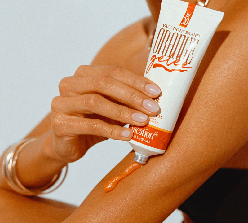a woman is applying orange gel to her arm