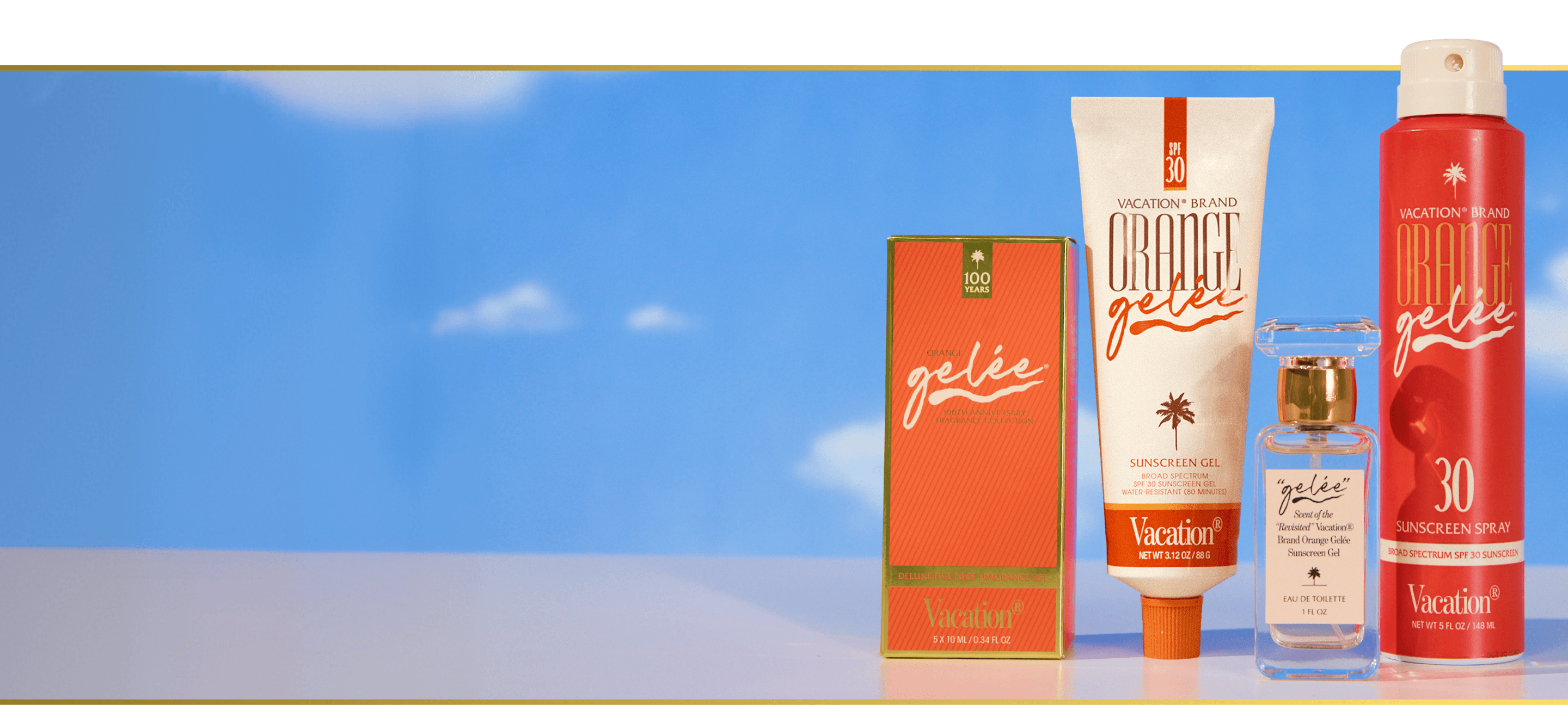 Vacation Brand "Orange Gelée" sunscreen gel, spray, perfume, and box against a blue sky.