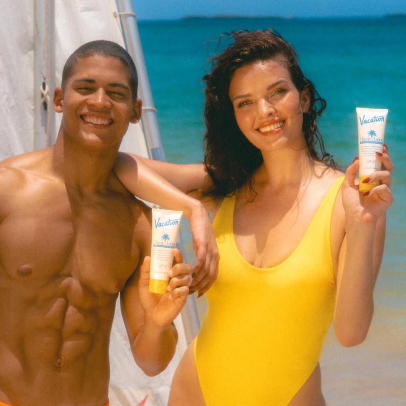 a man and a woman holding vacation sunscreen on the beach