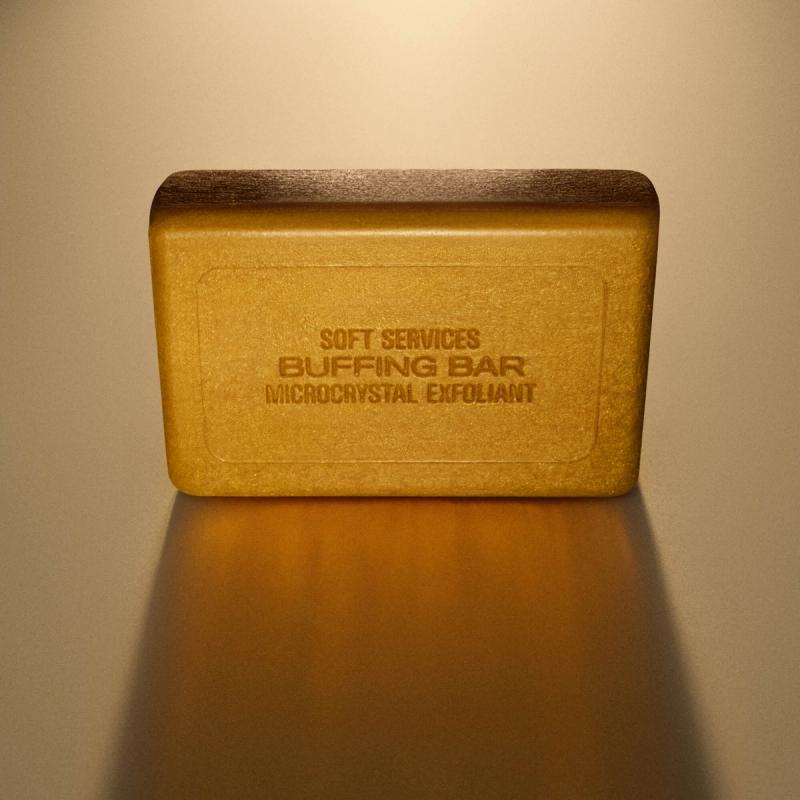 A golden-brown rectangular bar labeled "Soft Services Buffing Bar Microcrystal Exfoliant".